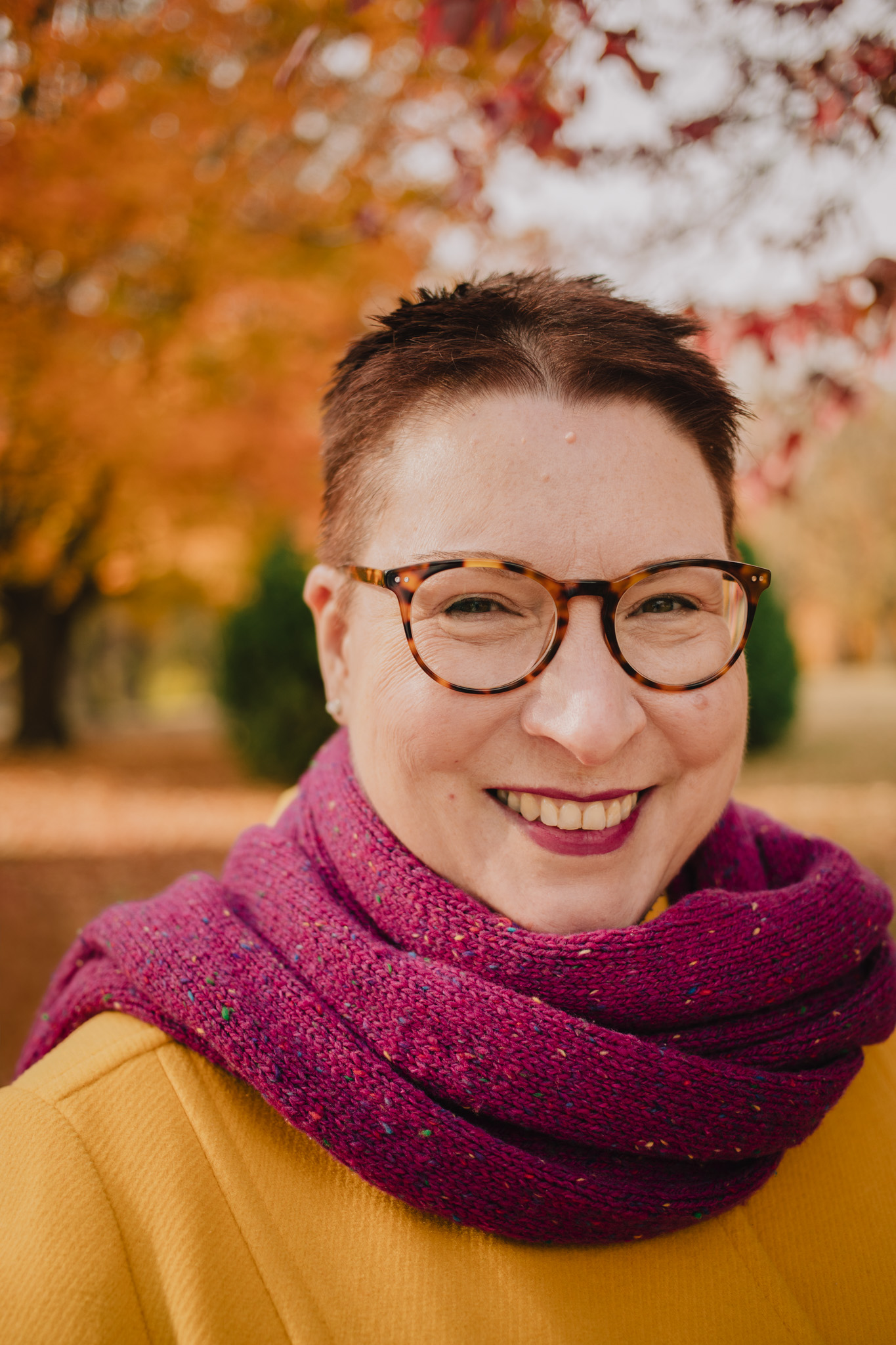 Cate Denial Headshot: white woman with short redish brown hair and glasses